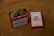 A red metal tin labeled 'Dad Grass' filled with dried hemp flowers sits next to a matching rectangular box. Both items feature vintage-style packaging design.