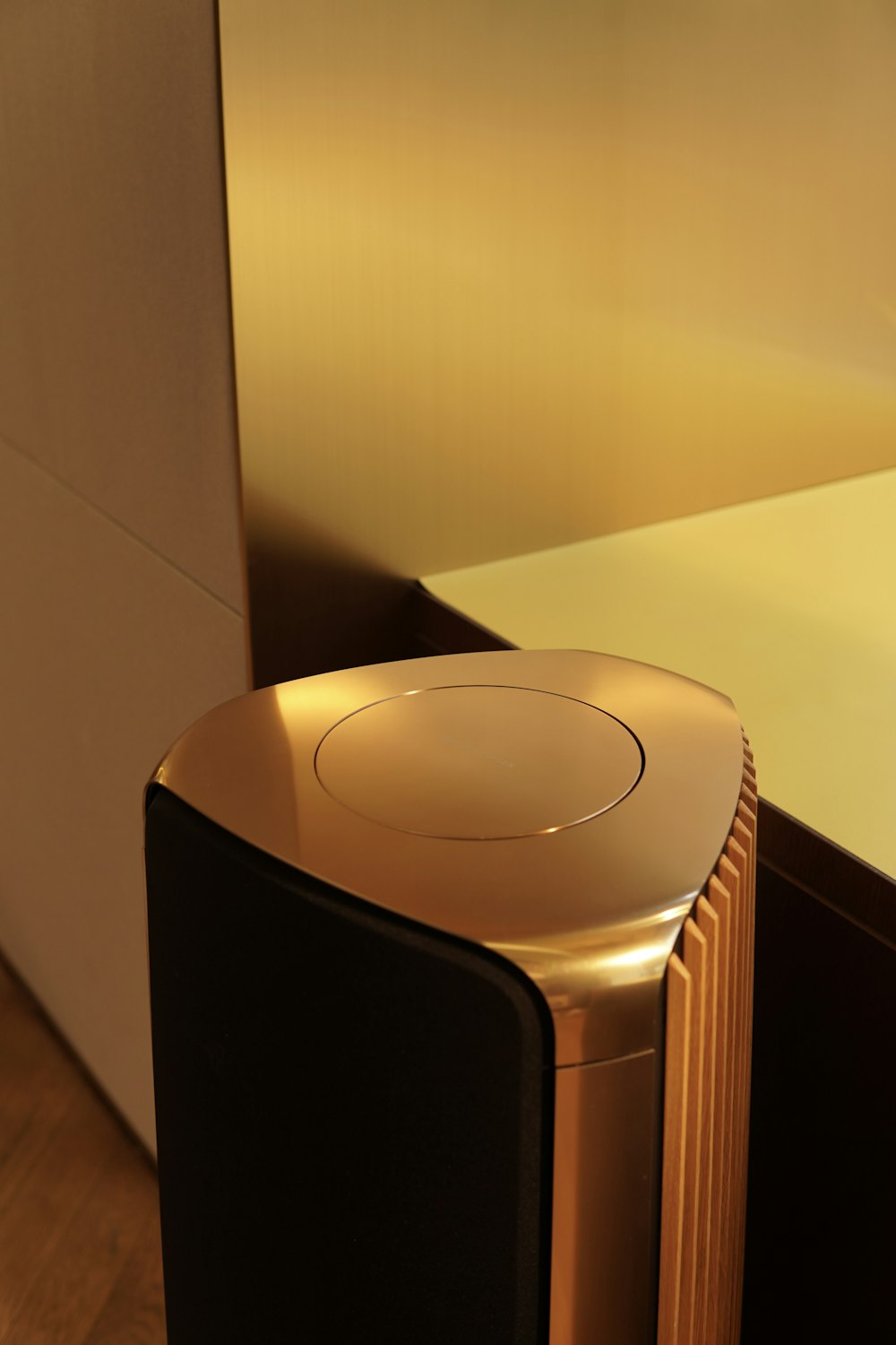 a gold and black speaker sitting on top of a wooden floor