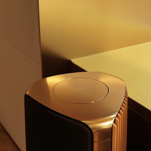 Gold and black speaker sitting on a wooden floor