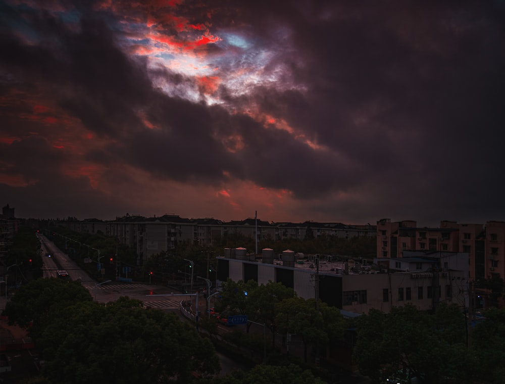 a red and blue sky with clouds and buildings