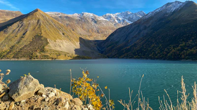 A serene Qinghai lake reflecting the colorful autumn foliage and distant snow-capped peaks.