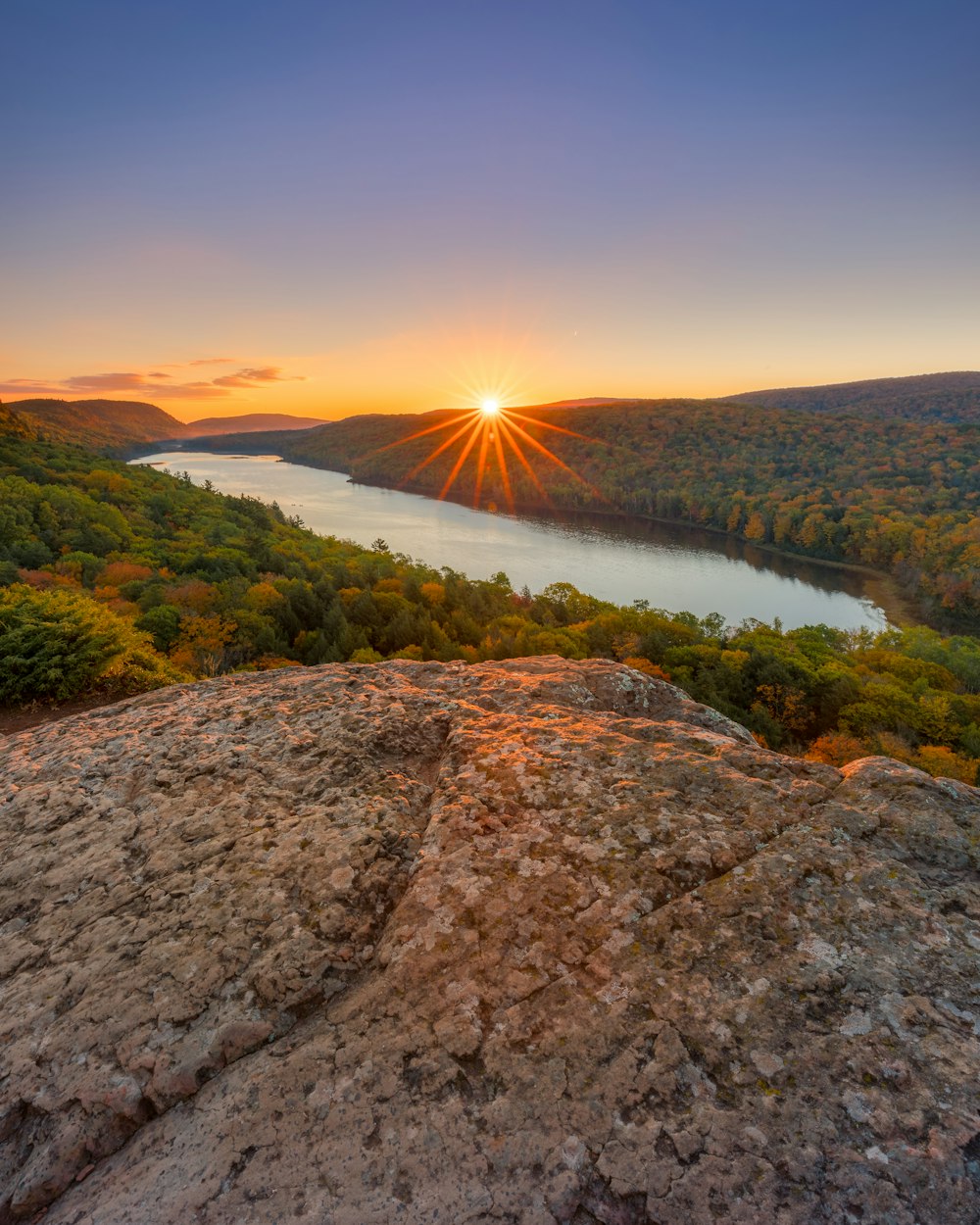 the sun is setting over a lake in the mountains