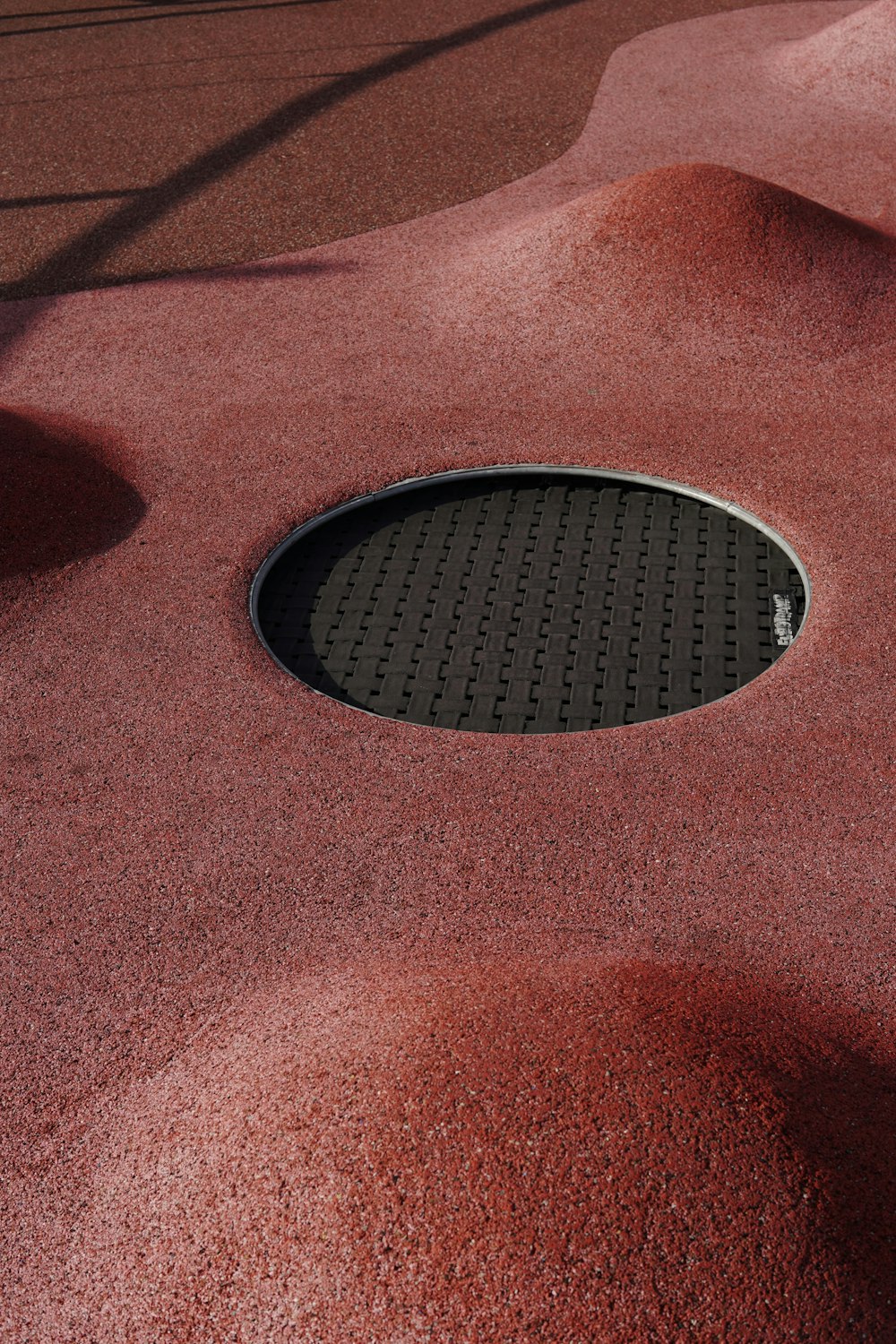 a round hole in the ground with red sand