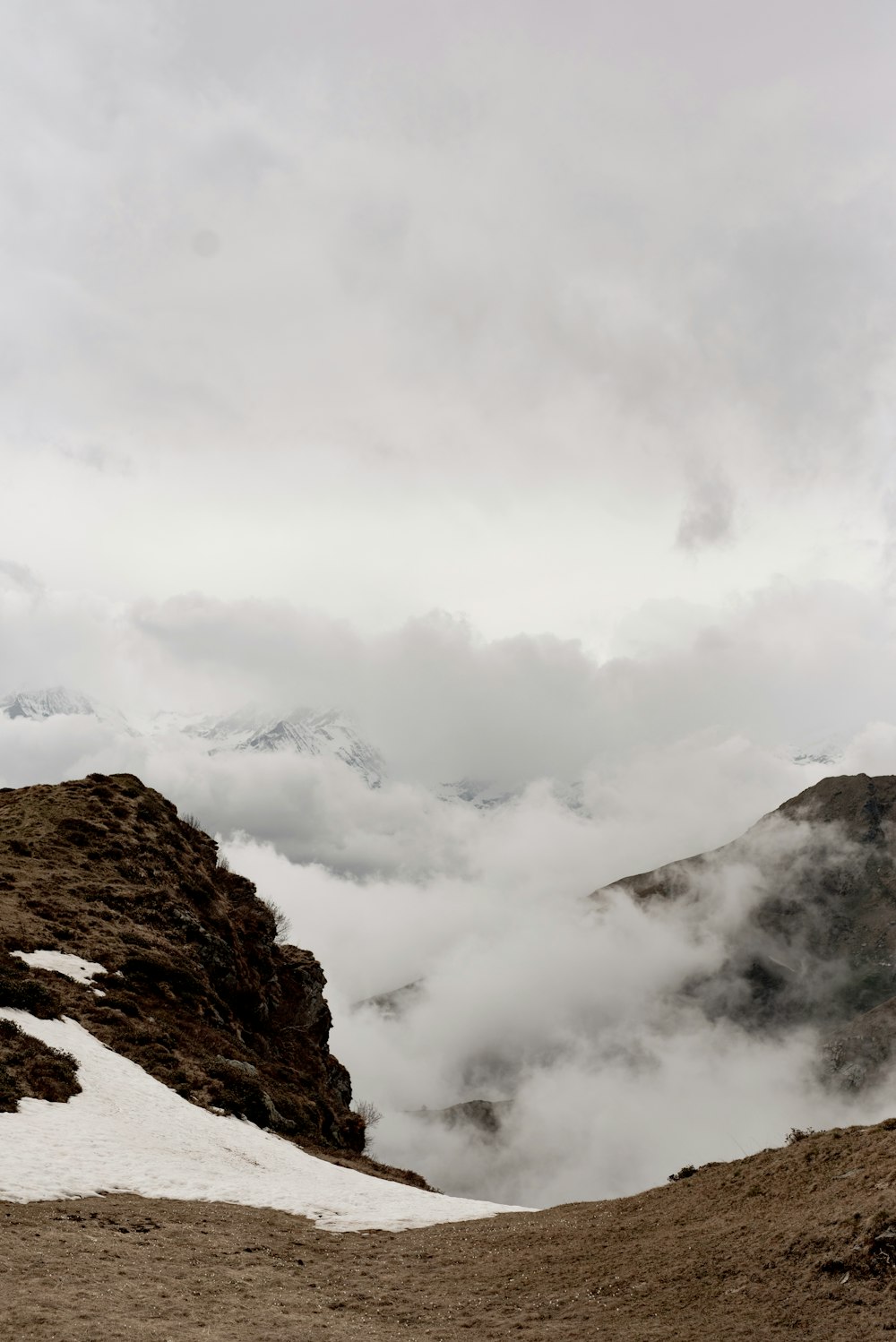 a mountain covered in snow and clouds on a cloudy day