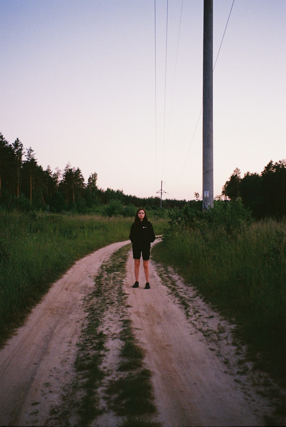 a person standing in the middle of a dirt road