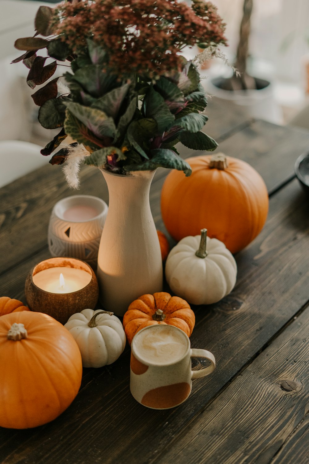 a wooden table topped with a vase filled with pumpkins
