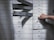 A hand holding a set of keys is reaching to open a series of safety deposit boxes. Some boxes are open, and the keyholes are visible. The boxes are metallic, numbered, and arranged in an organized manner.