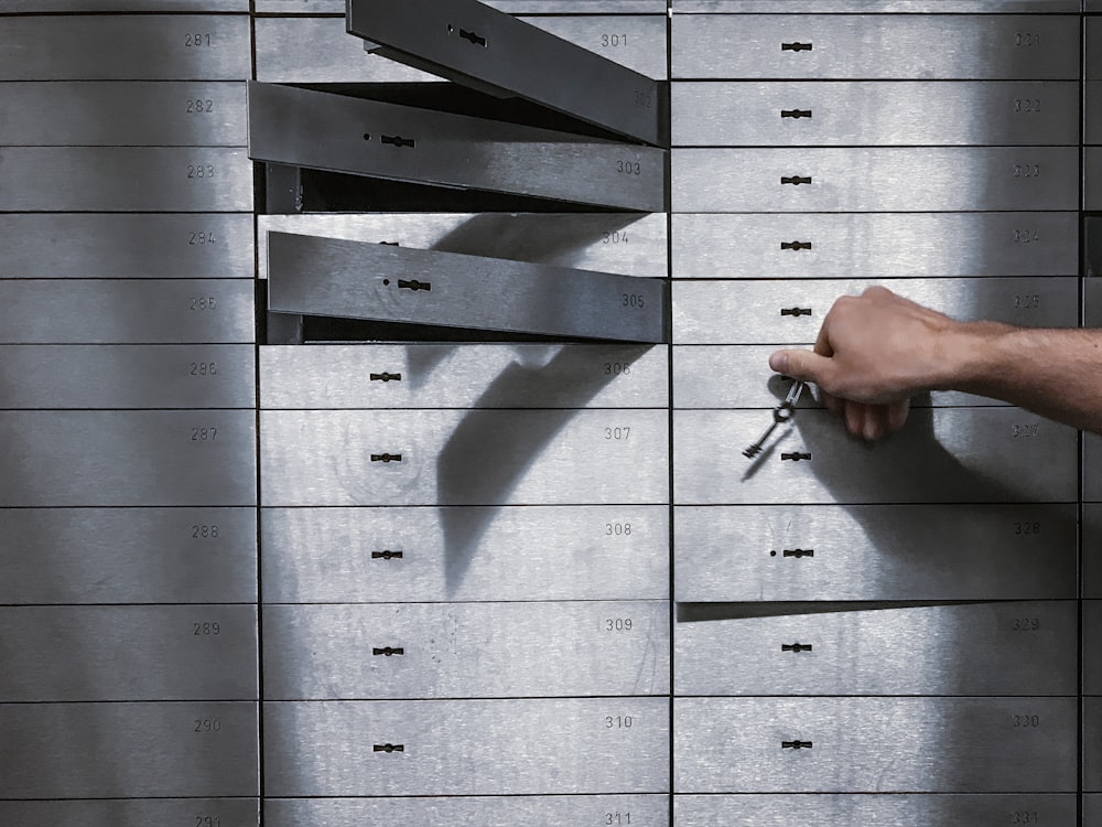 a hand is holding a bunch of keys in front of a metal locker