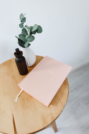 a wooden table topped with a vase filled with a plant