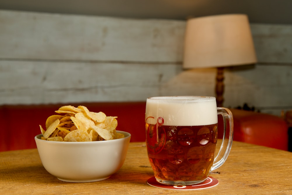 eine Schüssel Chips und ein Bier auf einem Tisch