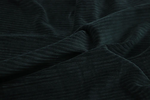 A rich, textured knitted fabric in deep black with golden threads catching the light.