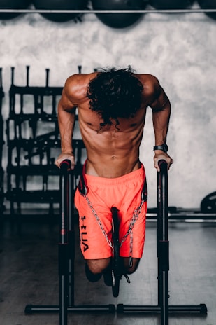 a shirtless man doing a pull up on a bar