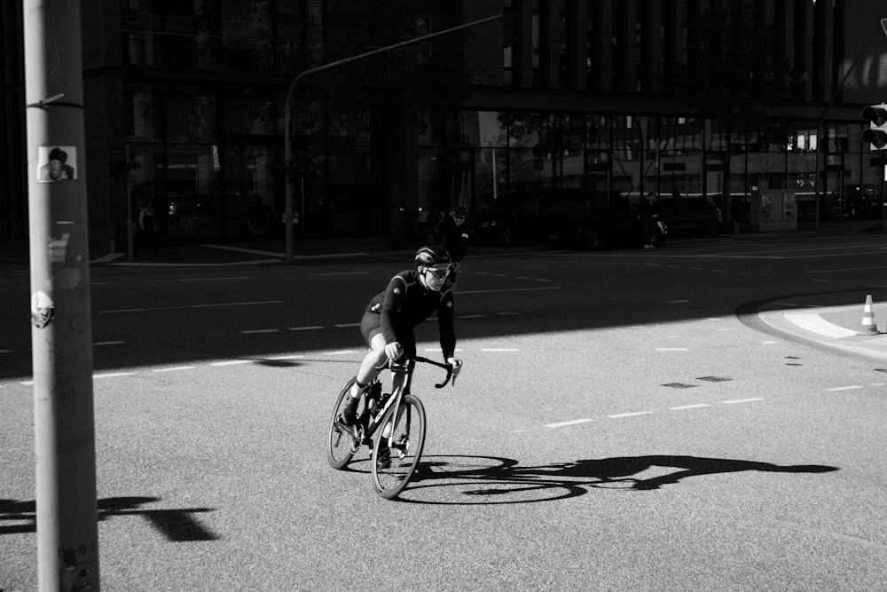 a man riding a bike down a street next to a traffic light