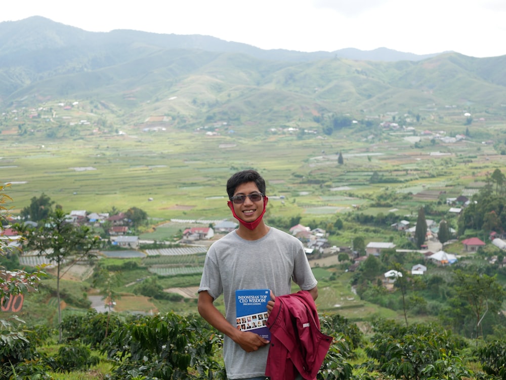 a man standing on top of a lush green hillside