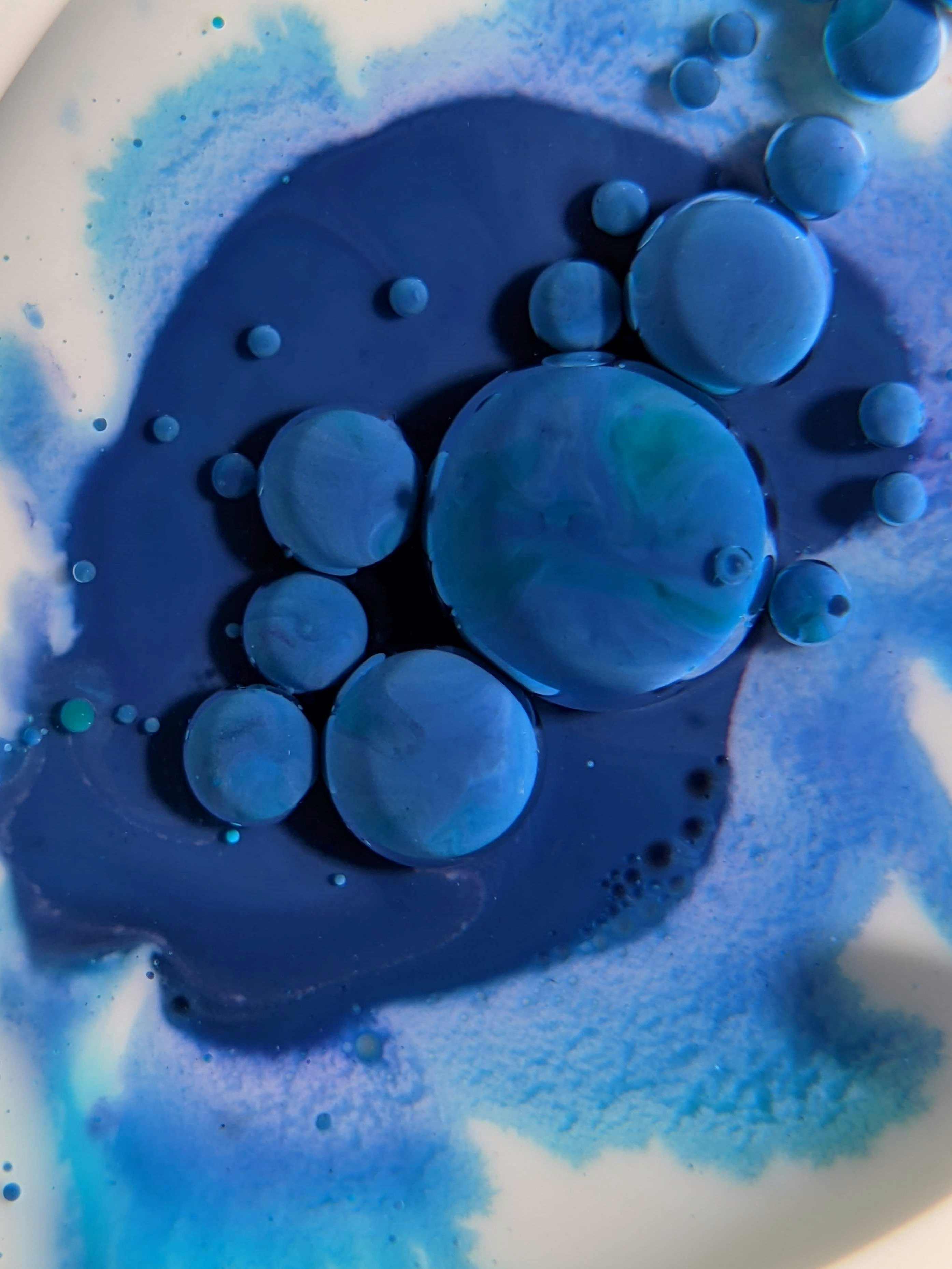 a white plate with blue and blue liquid on it