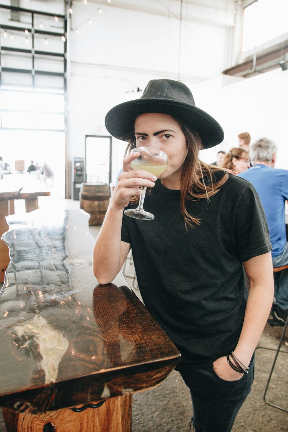 a man wearing a hat drinking a glass of wine
