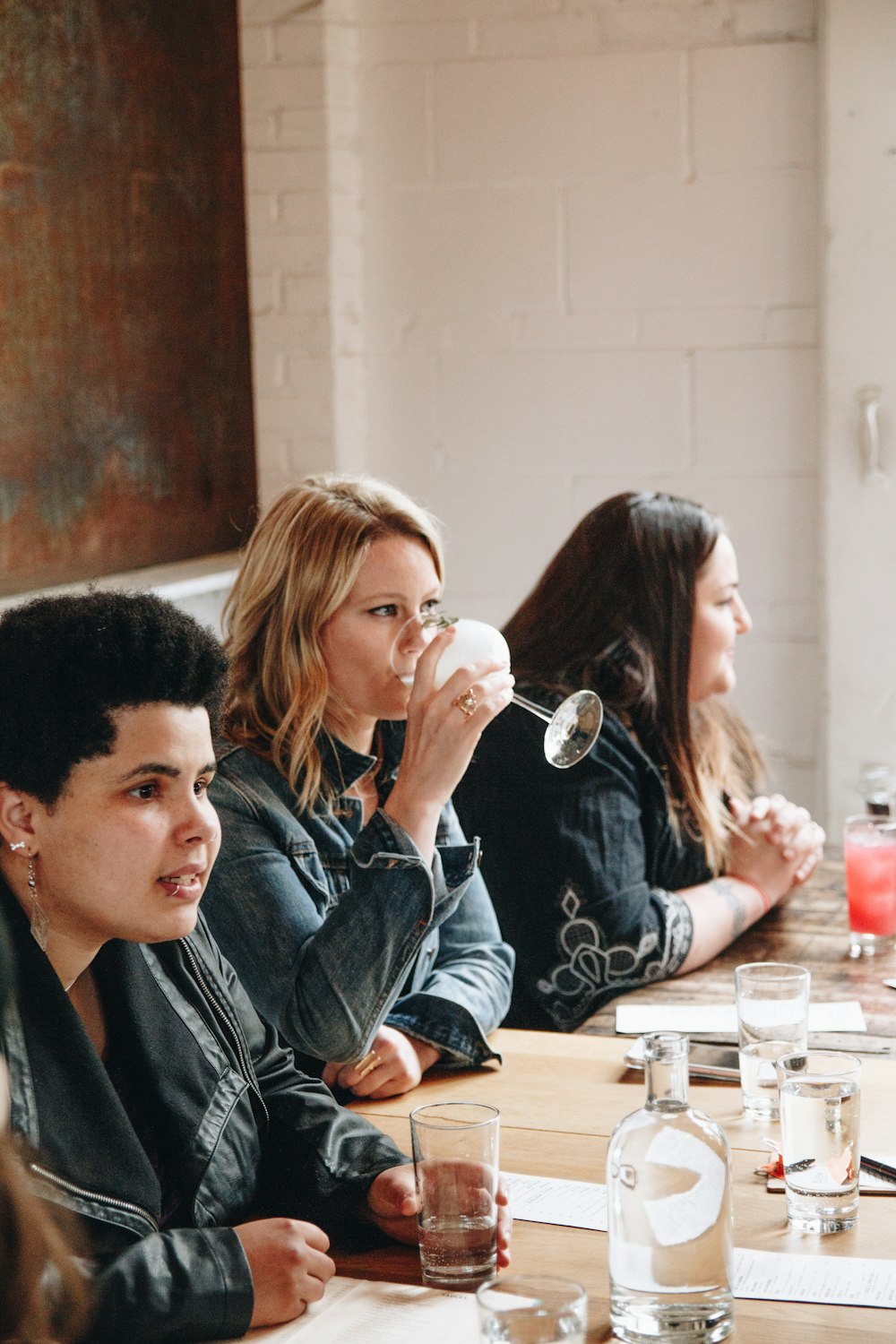 a group of women sitting at a table drinking from cups