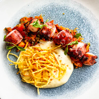 Close-up of a freshly grilled octopus dish served on rustic ceramic plates.