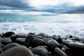 A slow-motion video still of waves crashing on a rocky shore under a cloudy sky