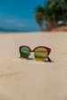 a pair of sunglasses sitting on top of a sandy beach