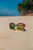 a pair of sunglasses sitting on top of a sandy beach