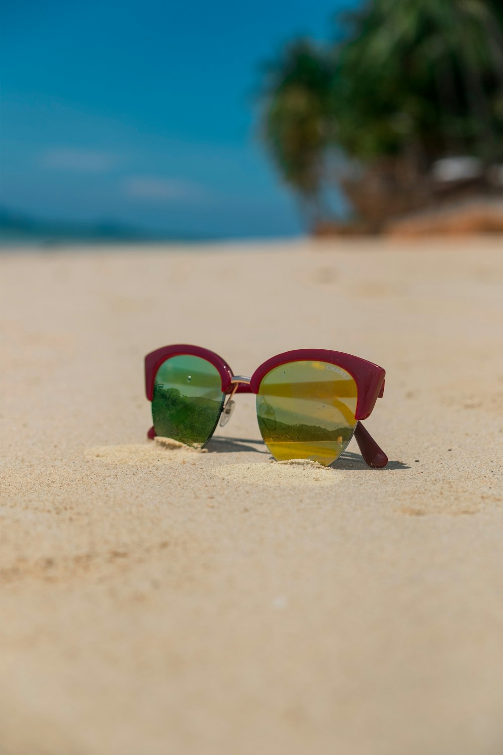 a pair of sunglasses sitting on top of a sandy beach