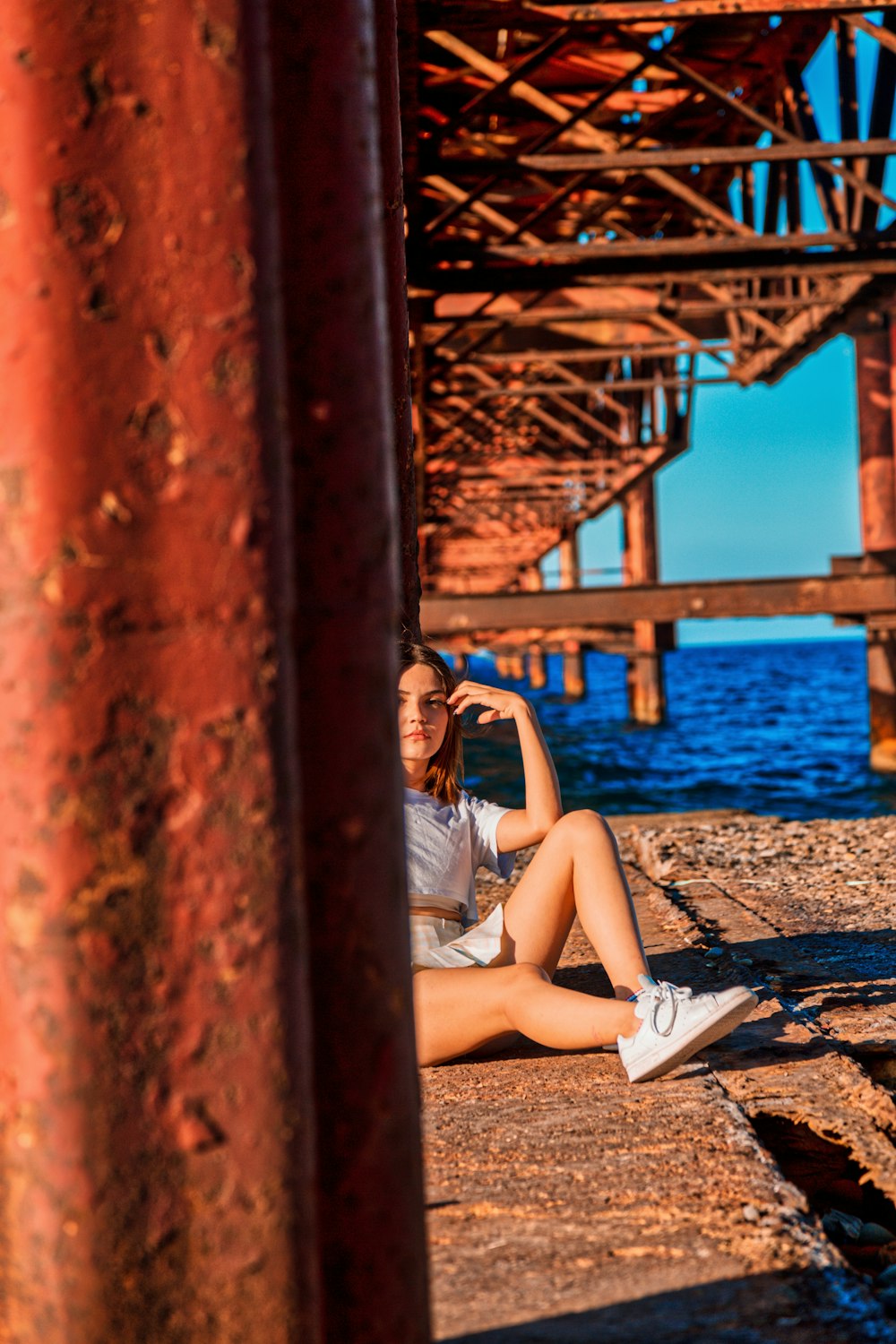 a woman sitting on the ground under a bridge