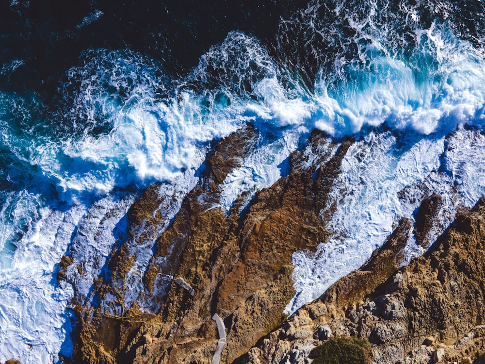 an aerial view of waves crashing on the rocks