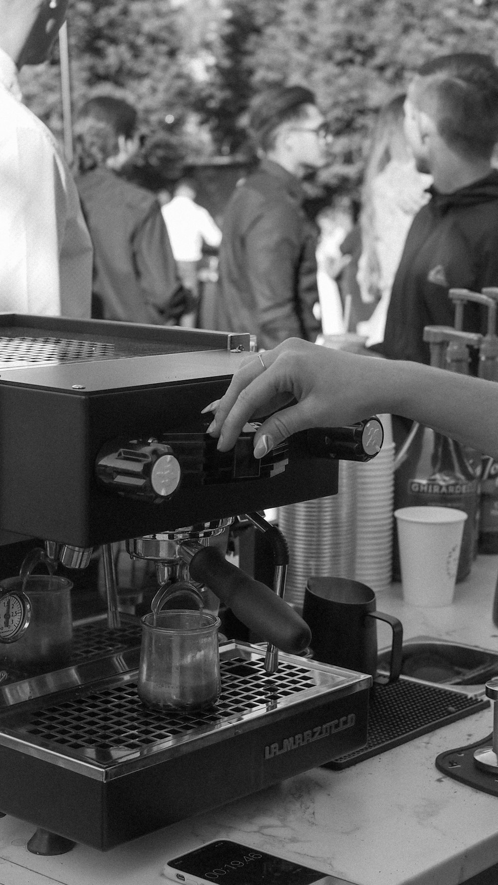 a black and white photo of a person using a coffee machine