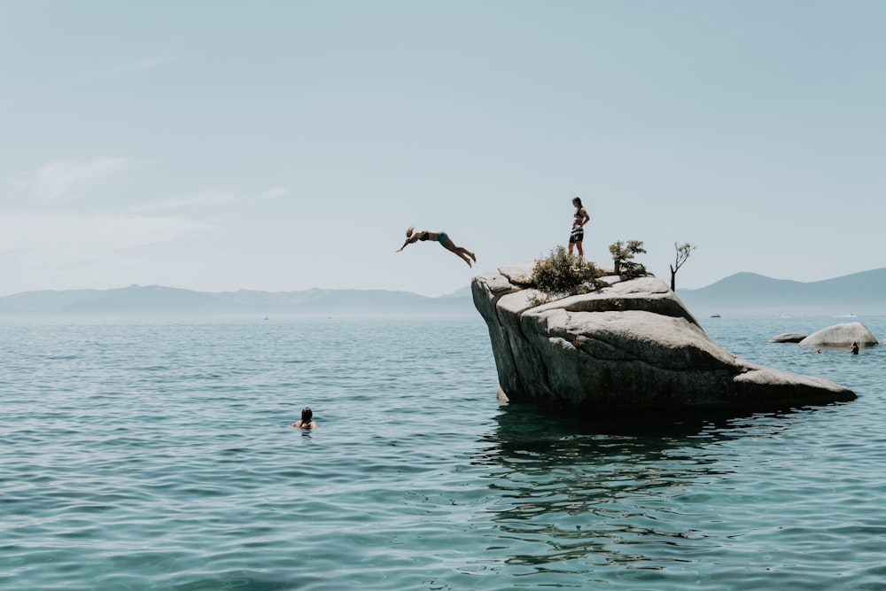 a group of people standing on top of a large rock in the middle of the