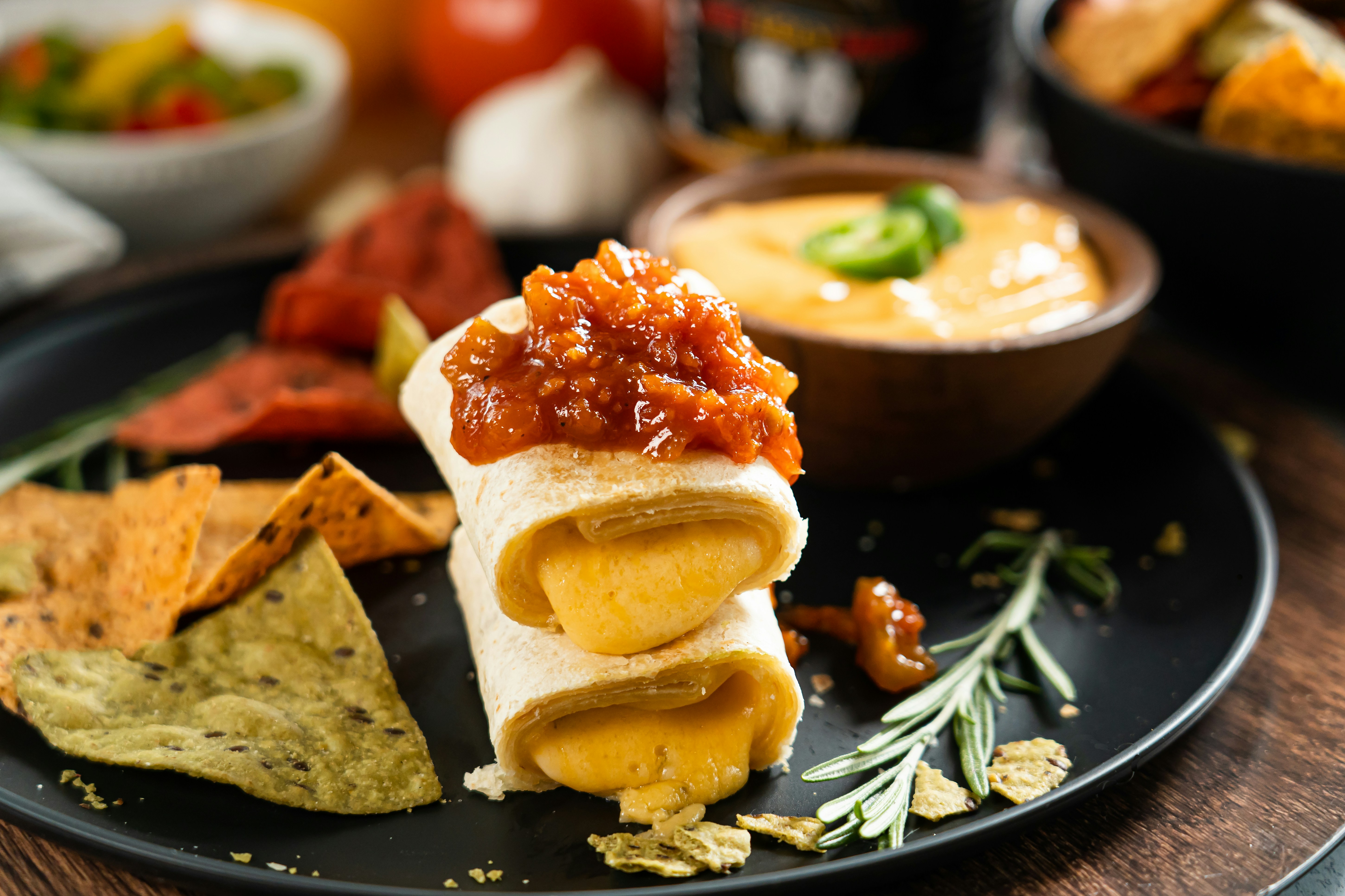Burritos with chips and dips on a black plate