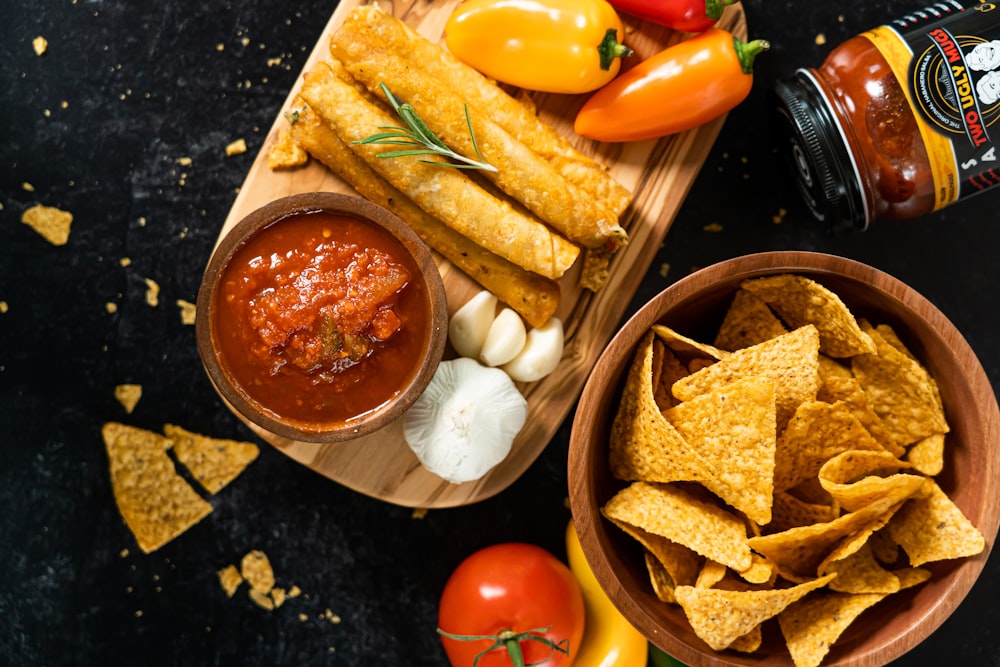 a wooden tray topped with chips and salsa