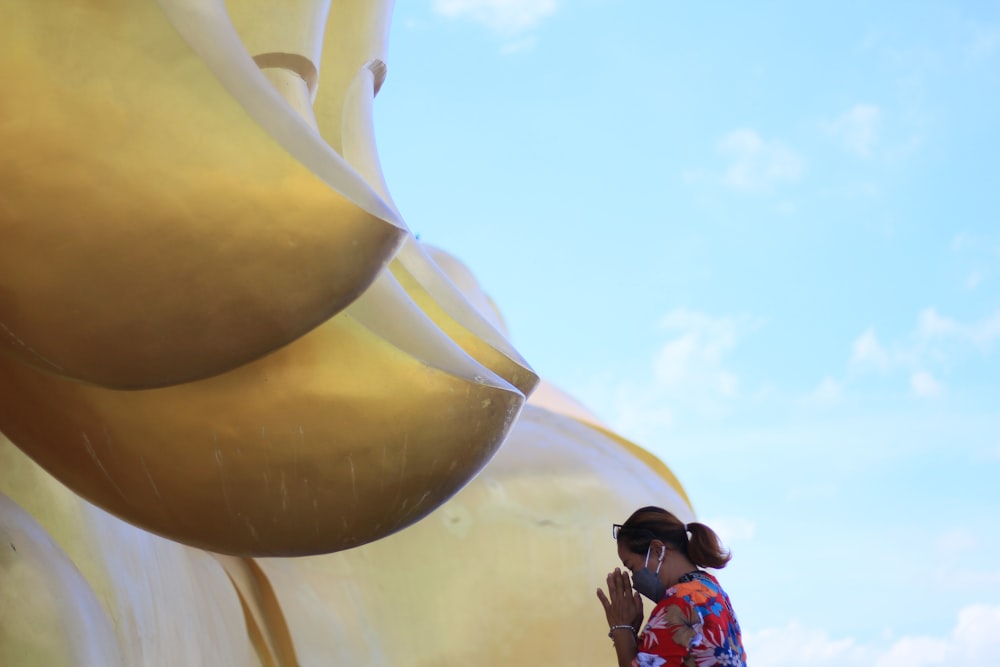 Una mujer de pie junto a un objeto amarillo gigante