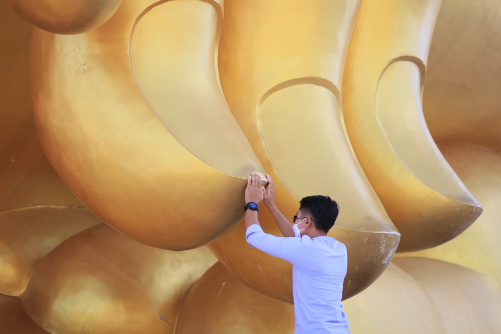 Un hombre de pie junto a una estatua dorada gigante