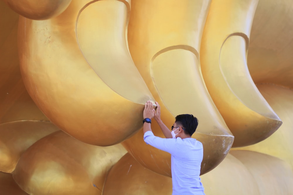 Un uomo in piedi accanto a una gigantesca statua dorata