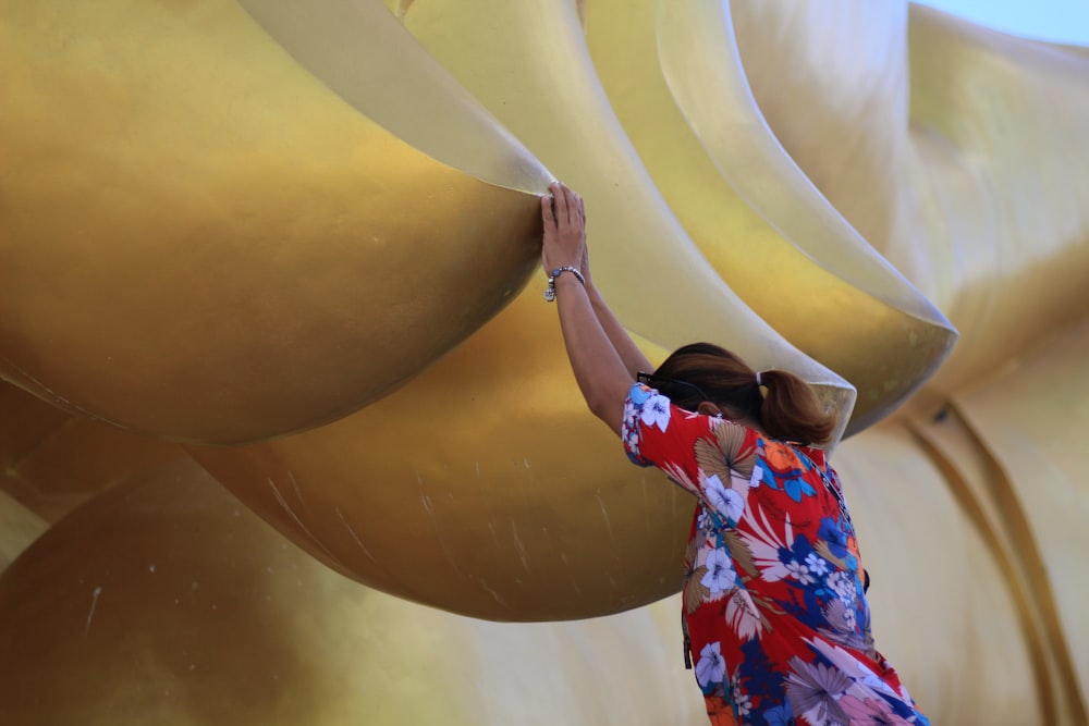 a woman in a colorful dress painting a large sculpture