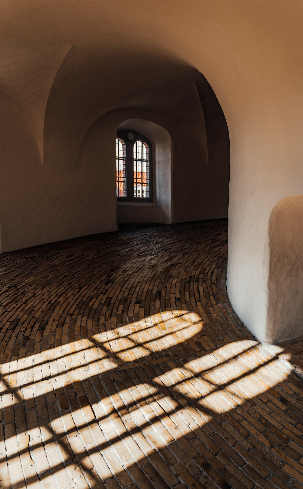 a room with a brick floor and arched windows