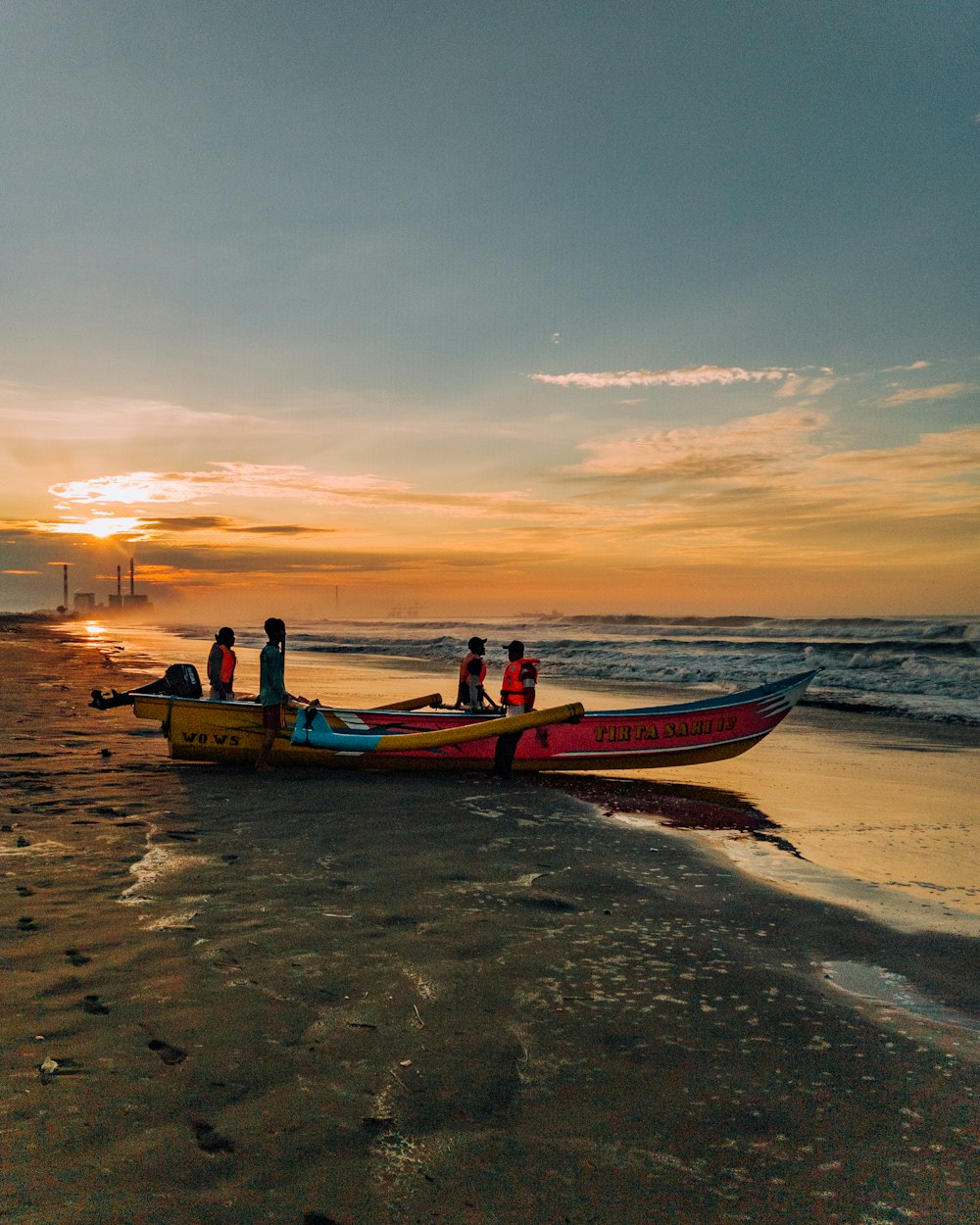 a group of people standing on top of a boat on a beach