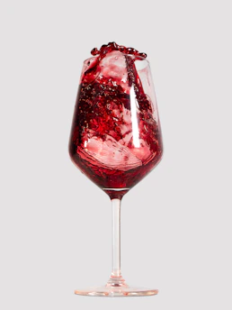 A vibrant close-up of red wine pouring into a glass, with warm ambient lighting.