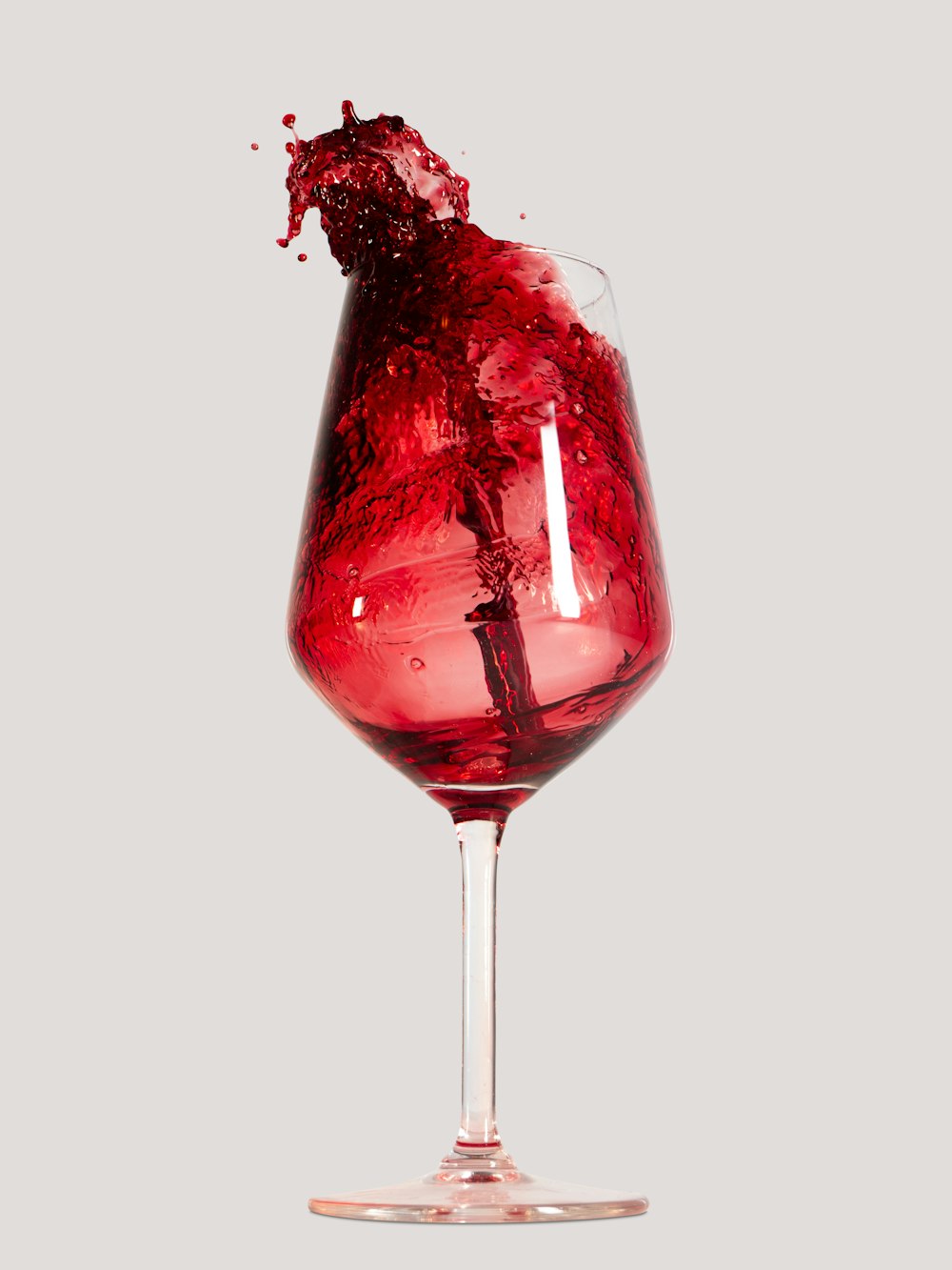 a wine glass with a red liquid splashing out of it