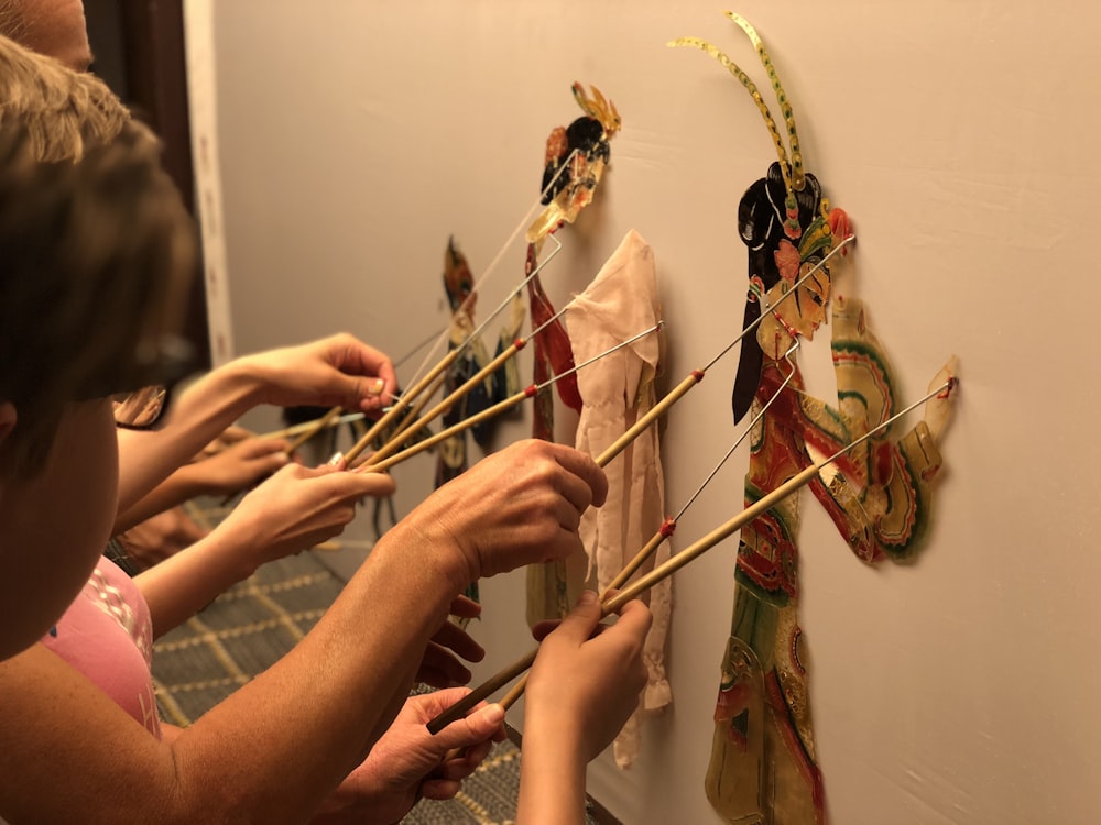 a group of people holding up sticks to a wall