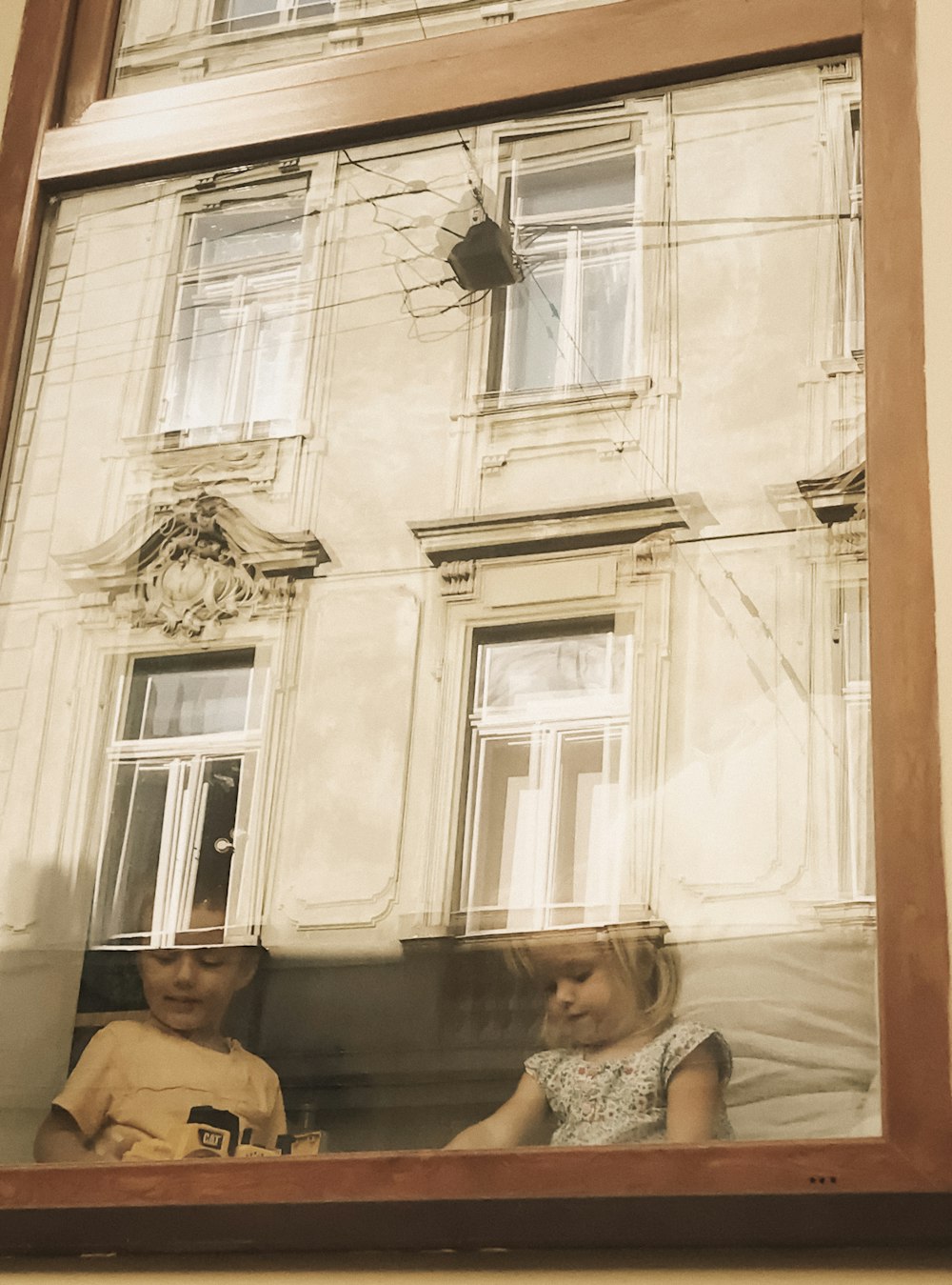 a picture of two children looking out of a window