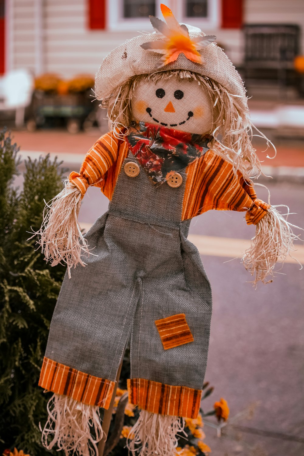 Una muñeca espantapájaros está parada frente a una casa