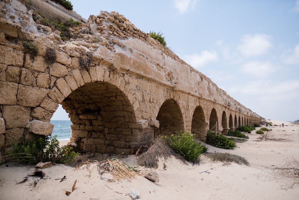 a stone bridge over a sandy beach next to the ocean