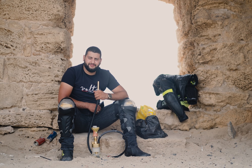 a man sitting on the ground next to a cave