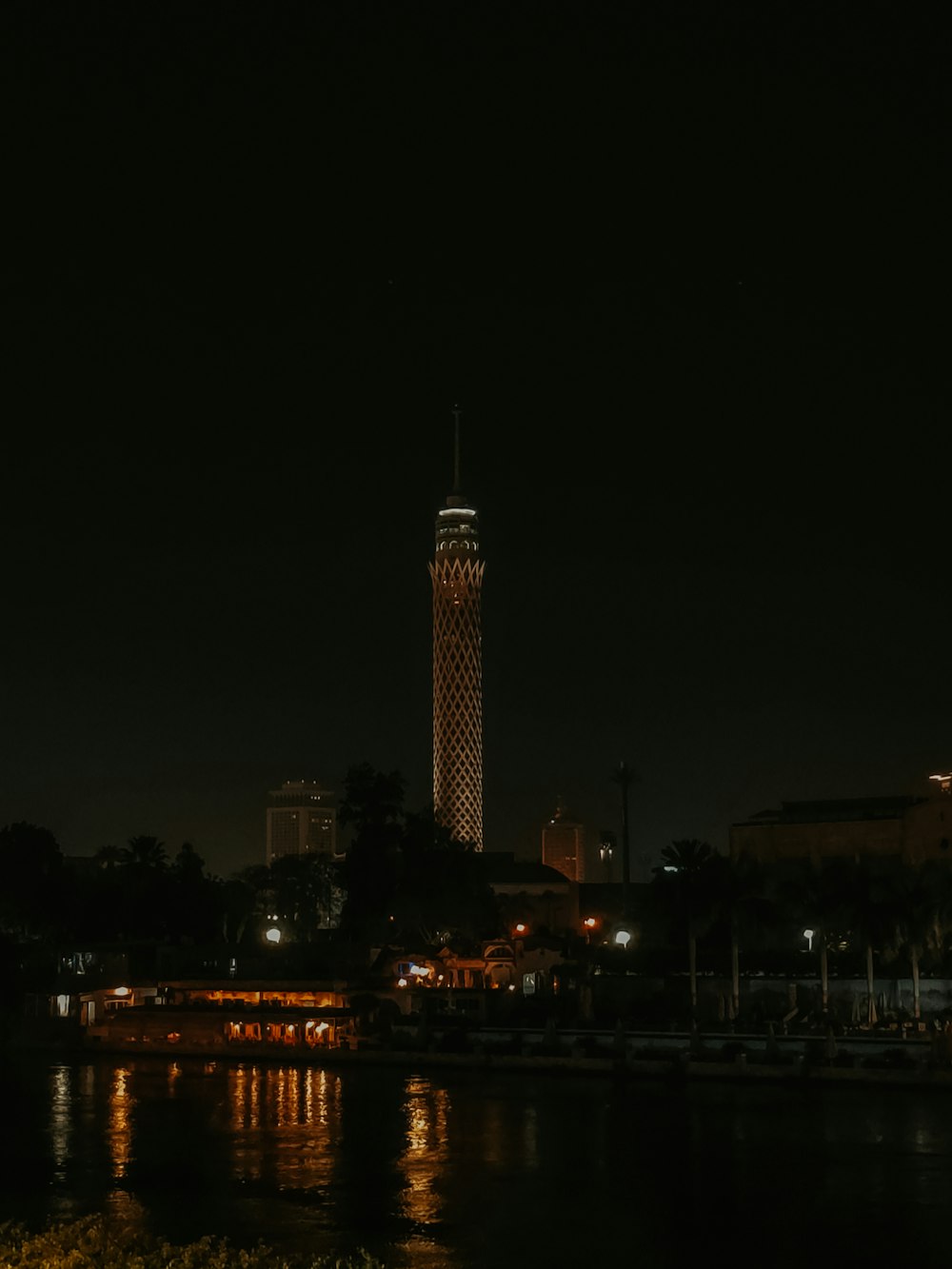 uma vista noturna de uma cidade com uma torre do relógio ao fundo
