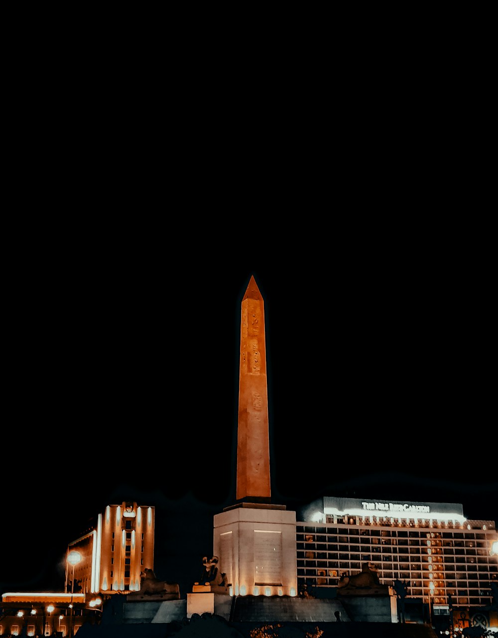 Ein hoher Obelisk vor einem Gebäude in der Nacht