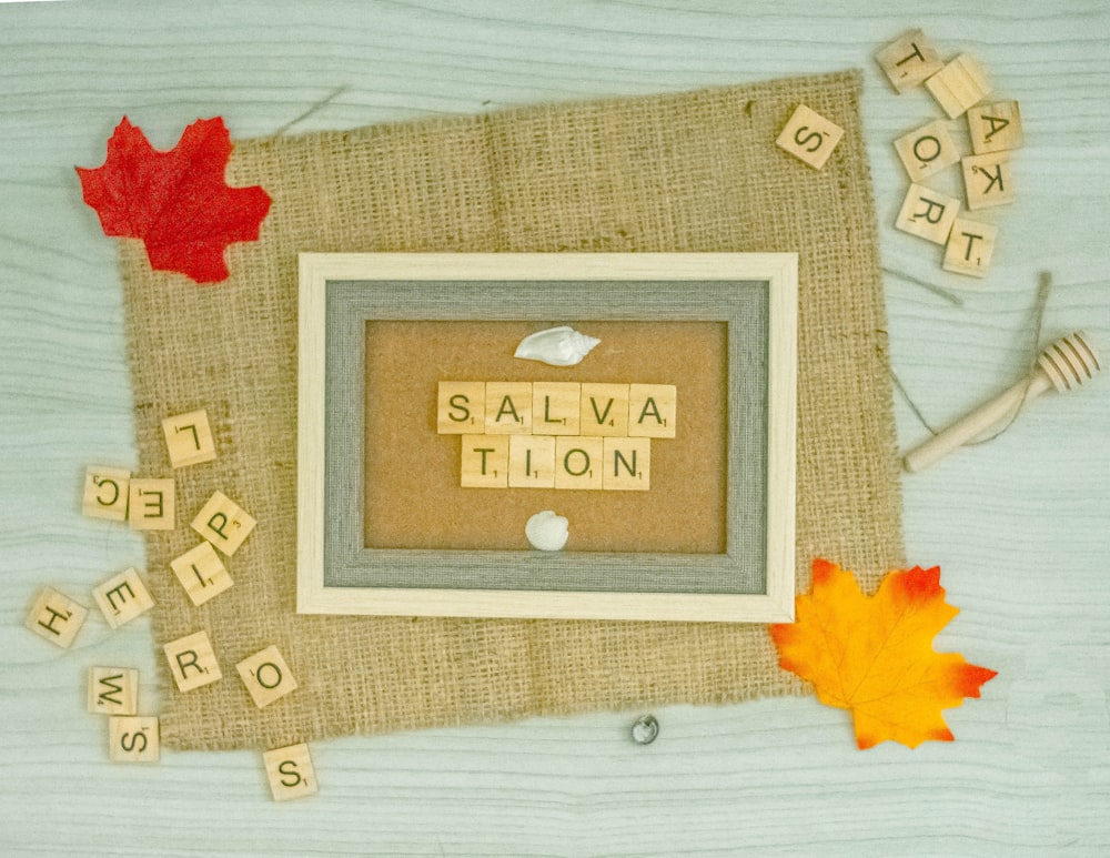 a picture frame with scrabble letters and autumn leaves