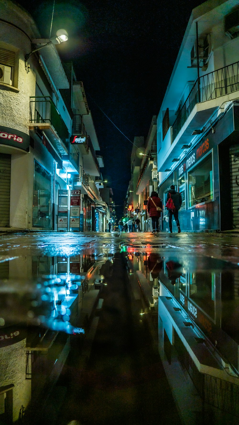 a person walking down a wet street at night
