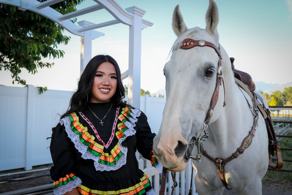 a woman standing next to a white horse